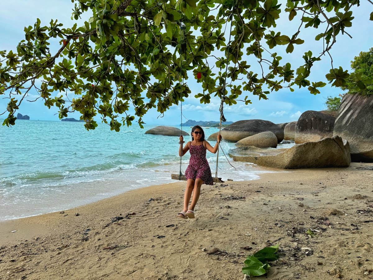 The stunning backdrop of rock formations frames my daughter's playful swing on the Wild Beach