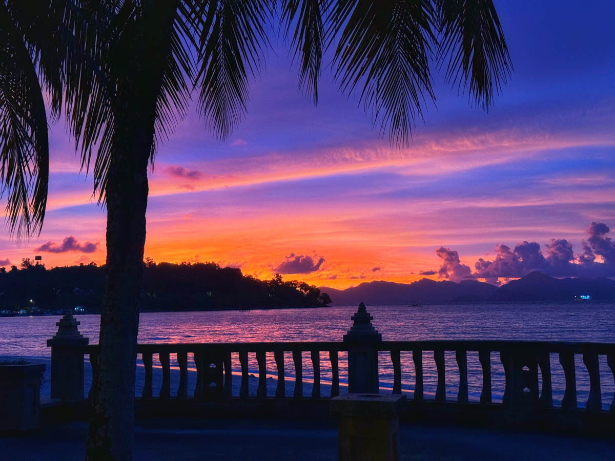 A breathtaking display of vibrant oranges, pinks, and purples illuminates the sky above the tranquil waters of Shark Bay Beach