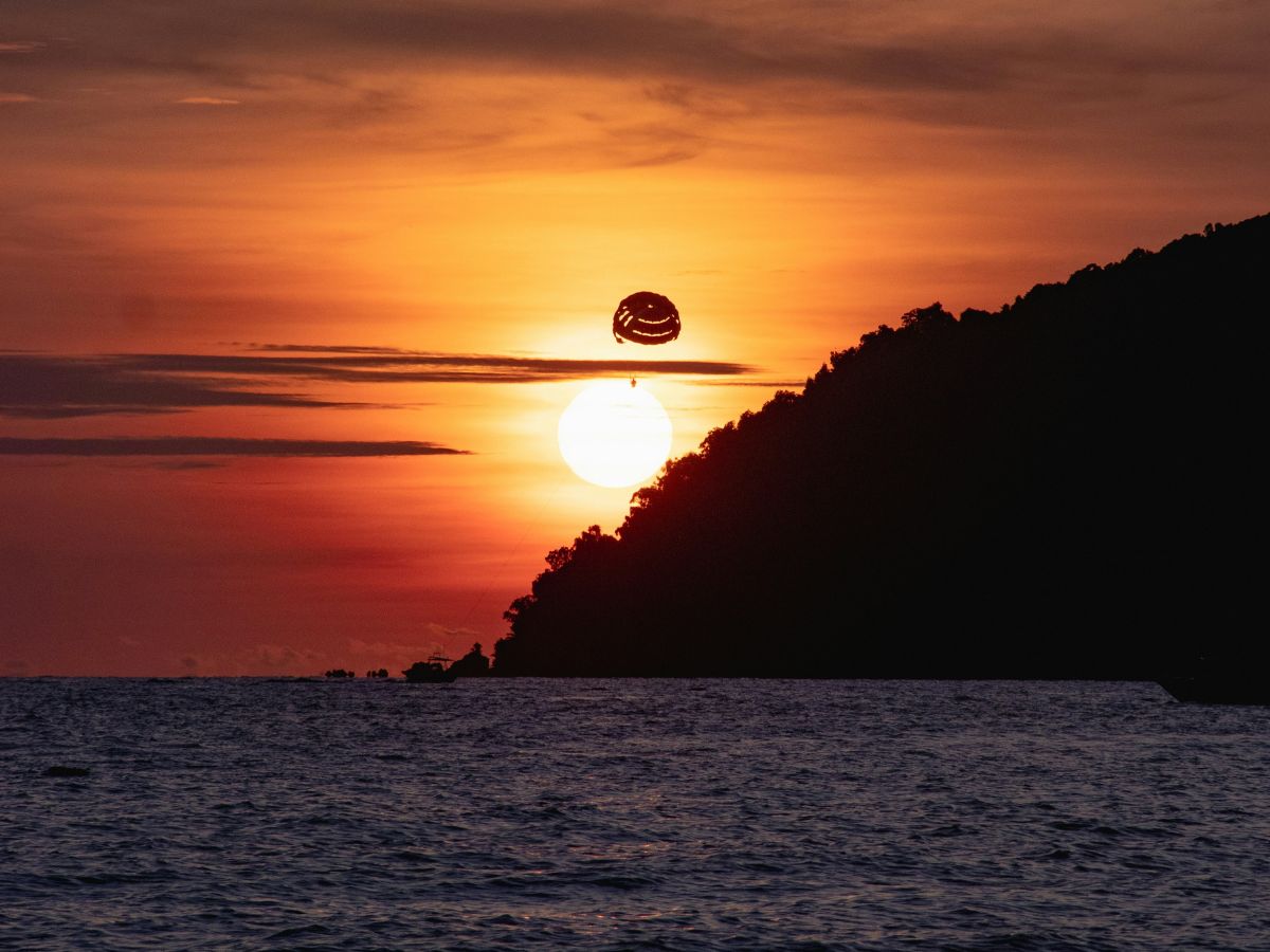 A parasailing flight over Pantai Tengah at sunset offers a breathtaking view of the waning sun