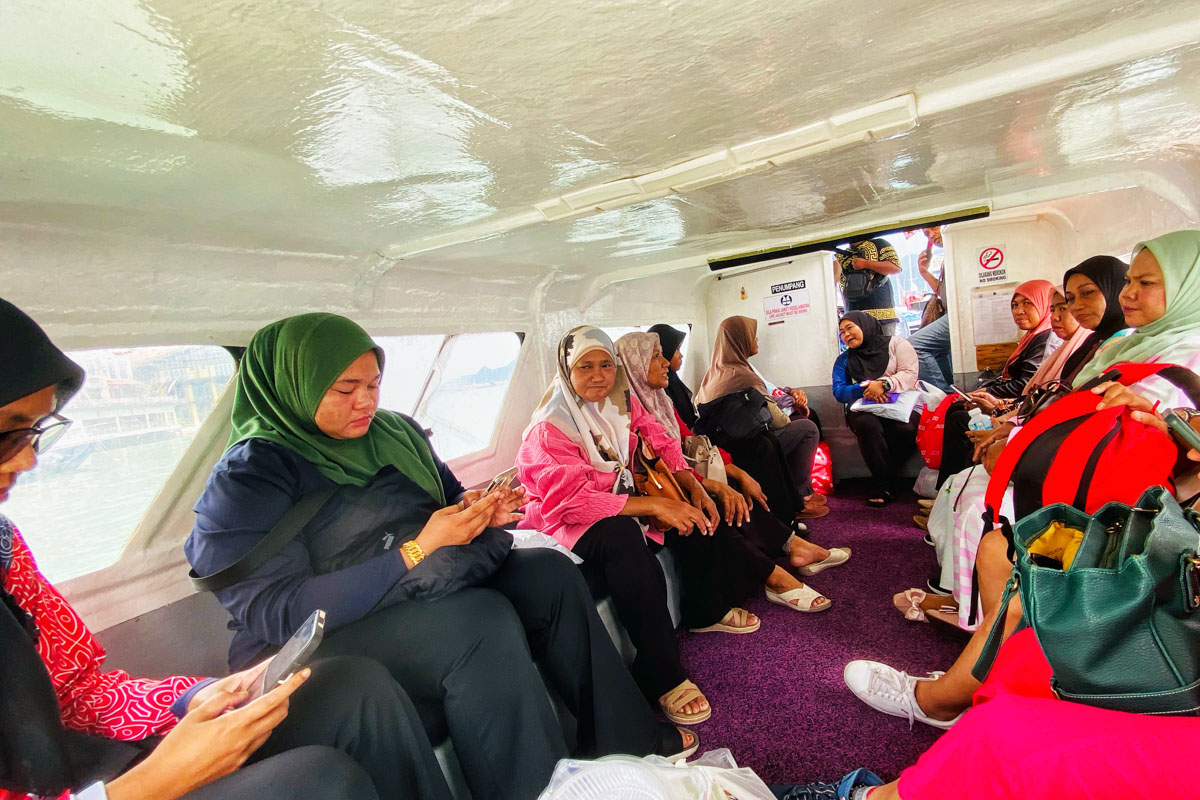 The local residents are busy on their phones while on a bumpy boat ride to Pulau Tuba