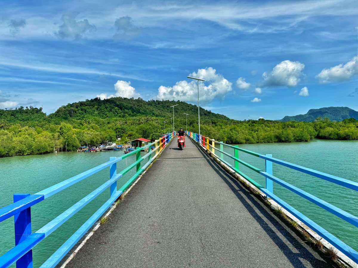 Narrow bridge connecting the islands of Tuba and Dayang Bunting is surrounded by lush green vegetation and azure water