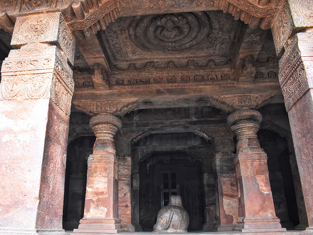 Nandi facing Garbhagriha surrounded by ornate pillars in Badami caves