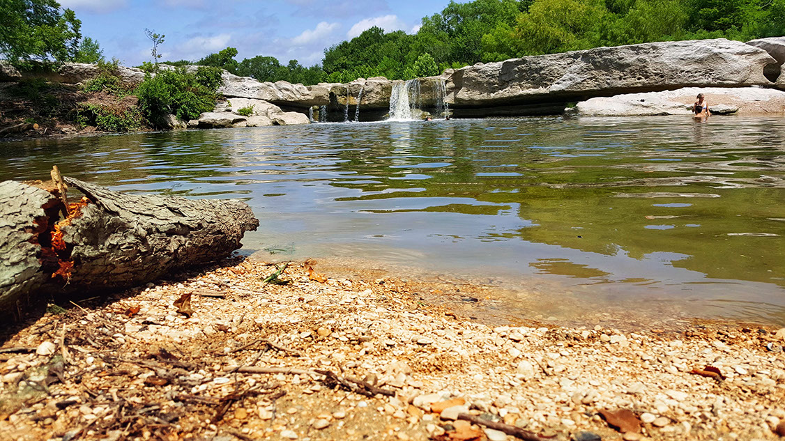 Natural swimming pool created by cascading waterfall in Onion Creek River