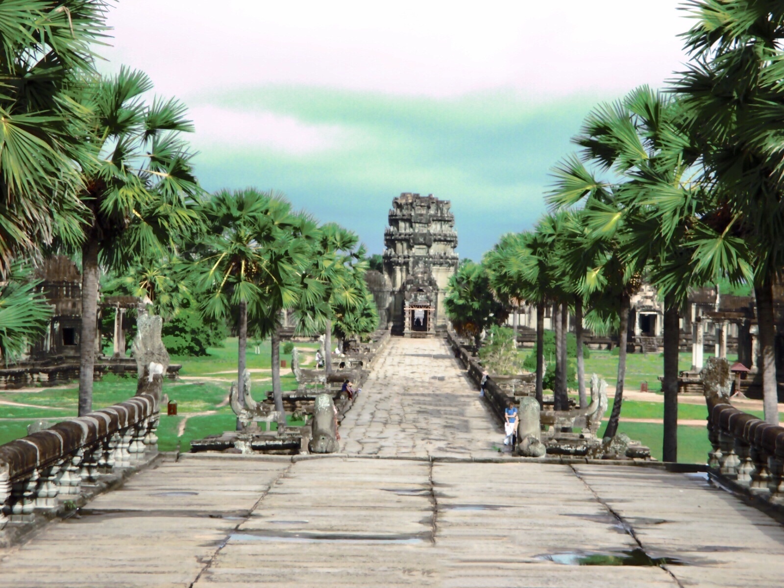 Picture-perfect entrance of Angkor Wat Temple surrounded by lush-green garden and palm trees