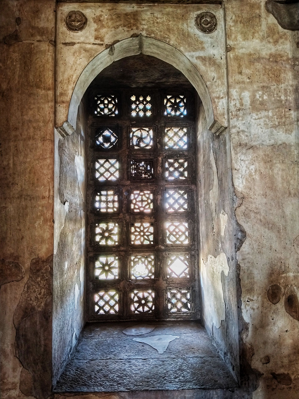 A window in Jami Masjid has geometric patterns carved into its jhali
