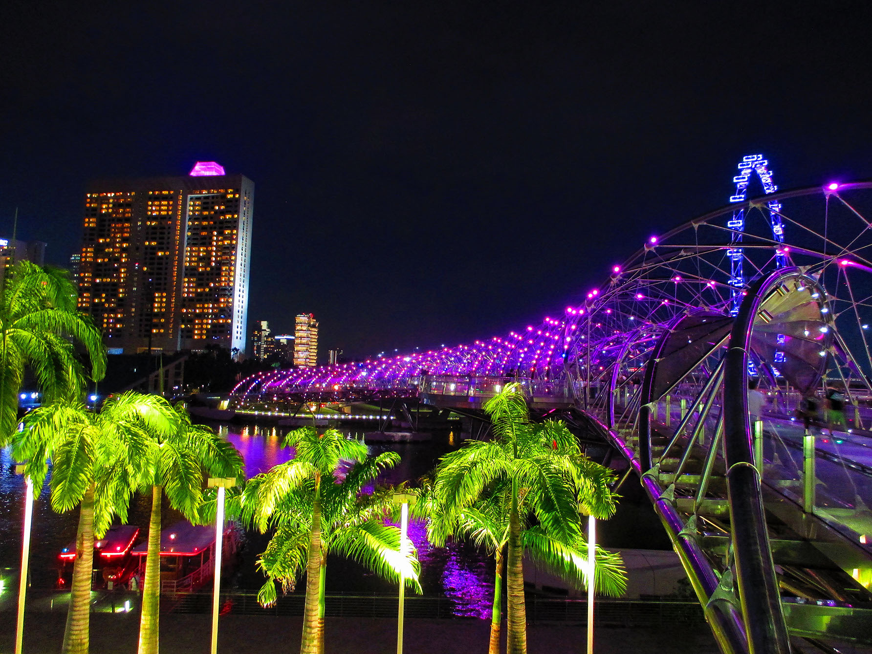 The Singapore Helix bridge is illuminated purple at night.