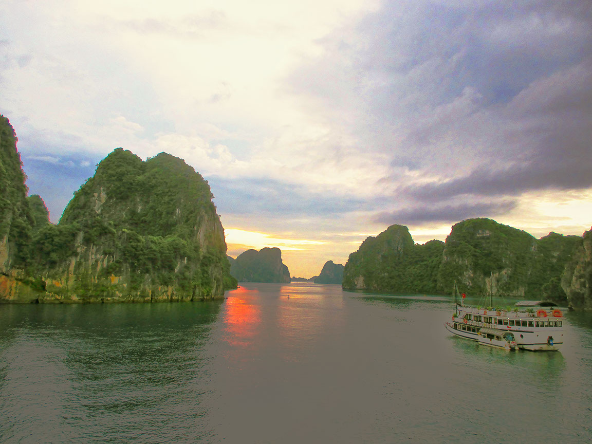 The view of Ha Long Bay at dawn with sunrays sneaking through the clouds