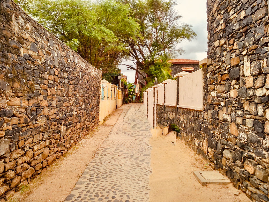 Narrow street with stoned walls on Goree Island reminds of its colonial style architecture.